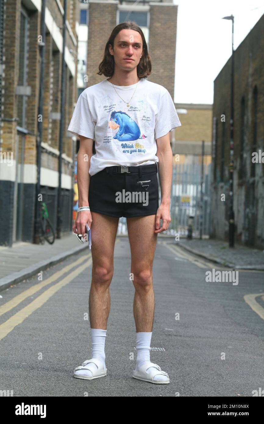 Cool rétro style vintage homme avec cheveux longs, short, imprimé t-shirt blanc, chaussettes blanches et baskets blanches baskets style urbain Banque D'Images Cool rétro style vintage homme avec cheveux longs, short, imprimé t-shirt blanc, chaussettes blanches et baskets blanches baskets style urbain Banque D'Images