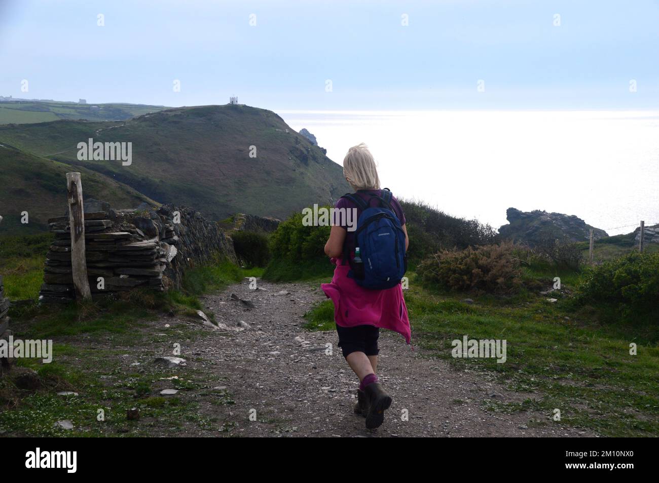Femme seule marchant jusqu'à la station de belvédère de Willapark près de Boscastle au coucher du soleil sur le South West Coastal Path à Cornwall, Angleterre, Royaume-Uni. Banque D'Images