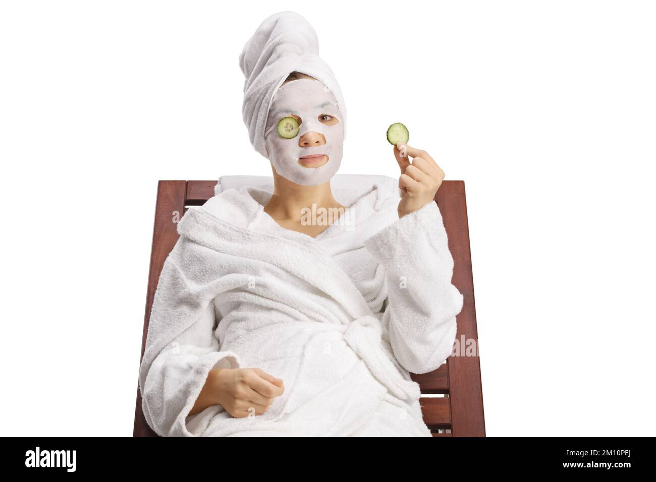 Femme dans un peignoir et cheveux enveloppés dans une serviette sur une chaise  longue avec une feuille masque facial et concombre sur les yeux isolés sur  fond blanc Photo Stock - Alamy