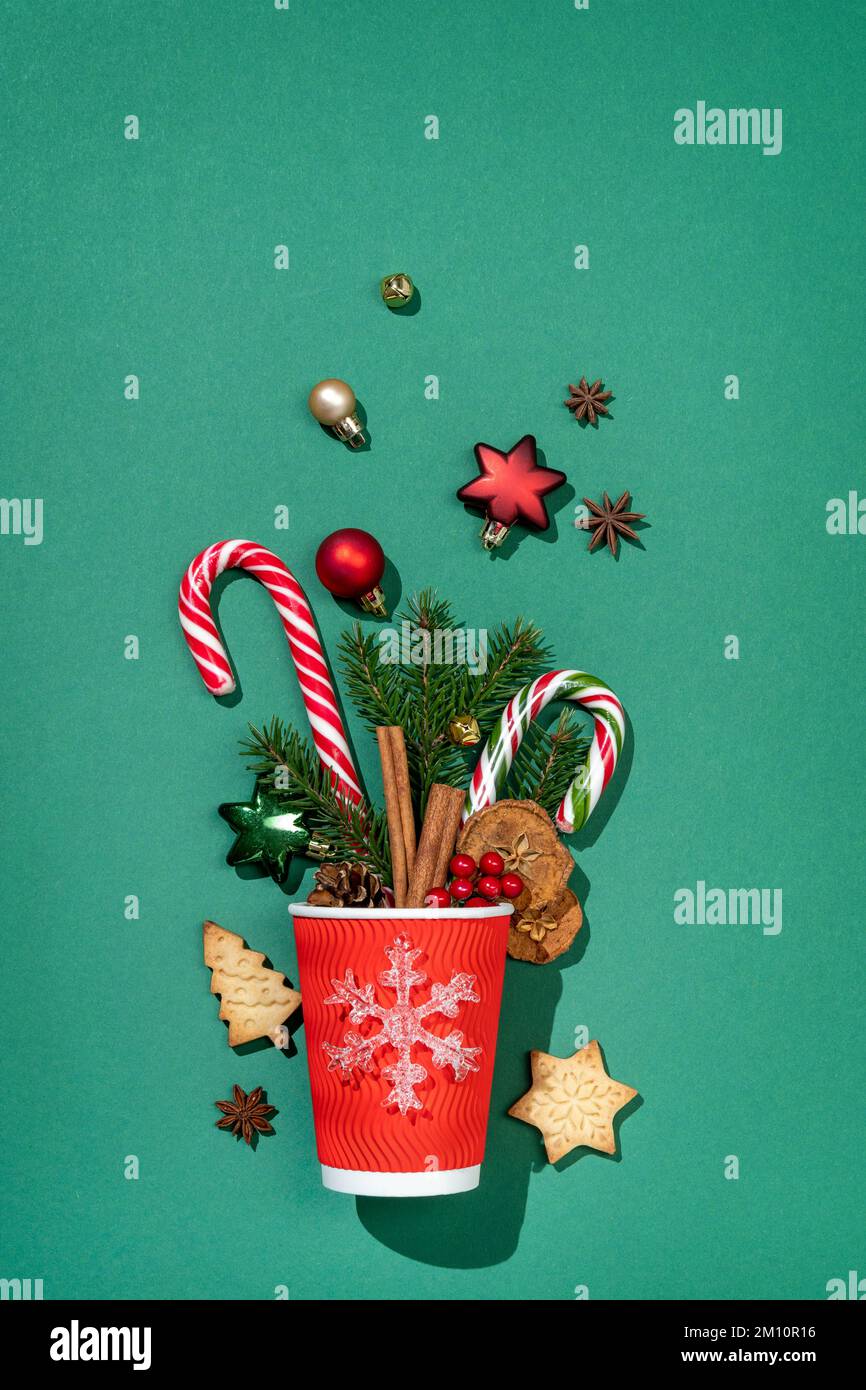 Tasse en papier rouge festive avec décorations sur fond vert. Joyeux Noël et bonne année concept Banque D'Images