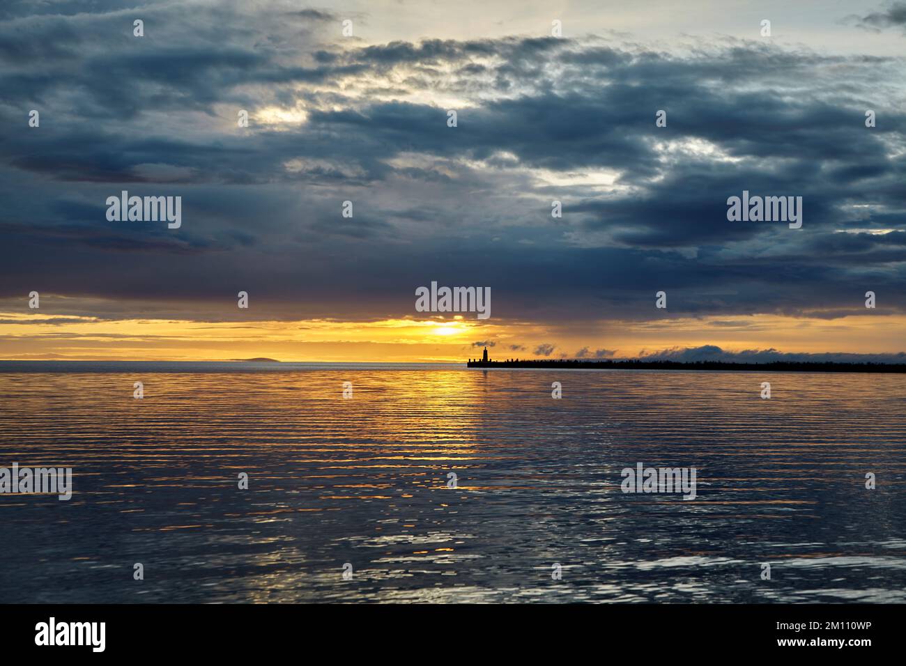 Coucher de soleil spectaculaire avec des nuages orageux avant l'orage. Jetée avec un phare sur fond de soleil couchant Banque D'Images