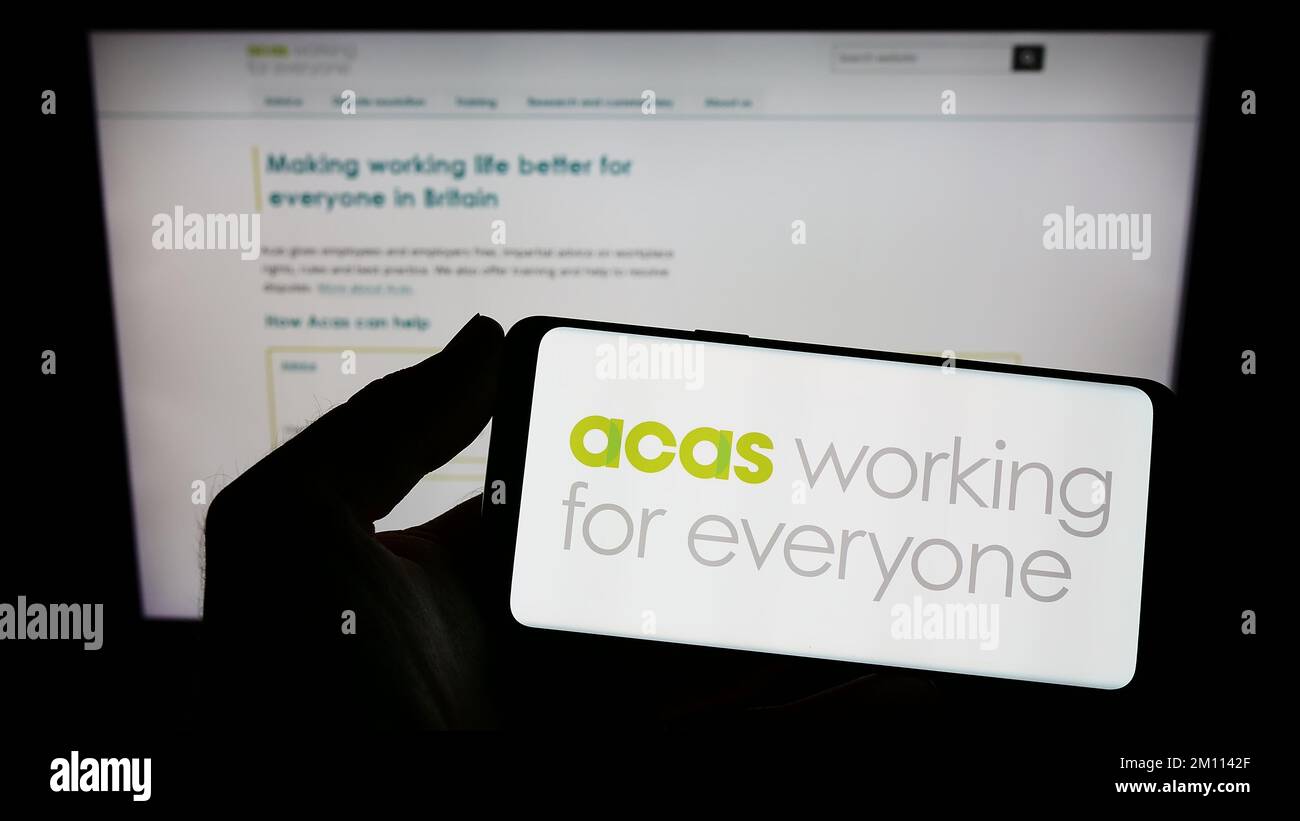 Titulaire d'un smartphone avec logo du Service consultatif, de conciliation et d'arbitrage (ACAS) à l'écran devant le site Web. Mise au point sur l'affichage du téléphone. Banque D'Images