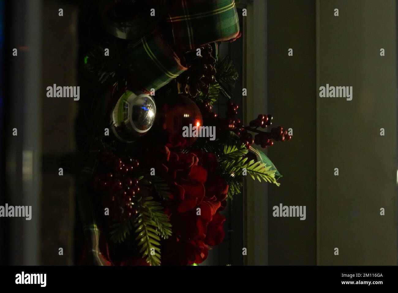 Une couronne ou un arrangement de porte de Noël avec le reflet de la véranda avant dans les boules Banque D'Images