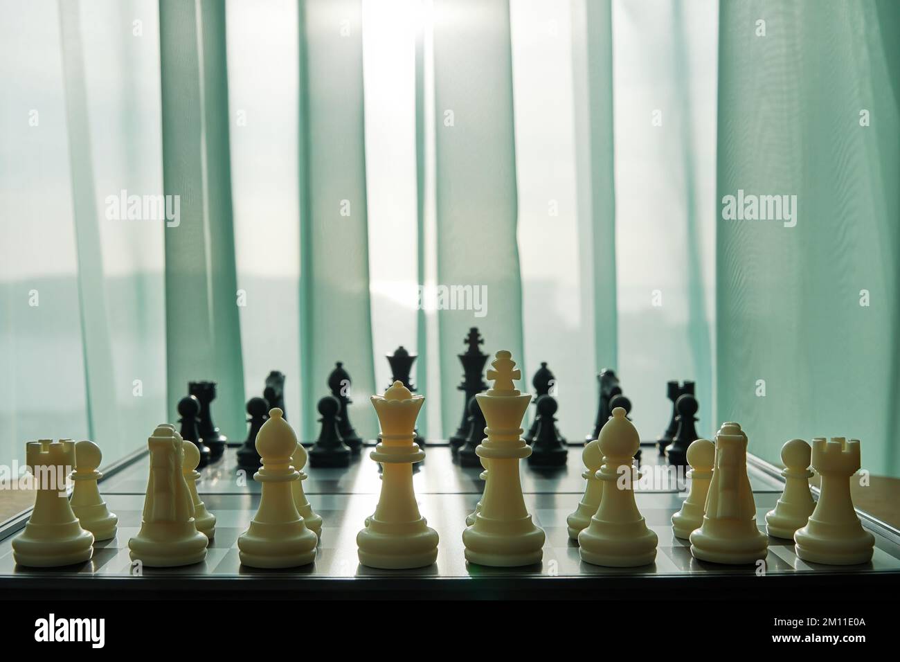 Vue arrière de la planche d'échecs prête pour le jeu dans la chambre près de la fenêtre. Concept de jeux intellectuels et d'activités de loisirs Banque D'Images