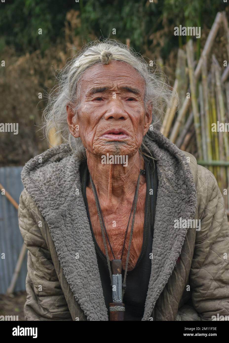 Ziro, Arunachal Pradesh, Inde - 02 19 2013 : Portrait de l'ancien homme tribal des Apatani avec tatouage traditionnel au menton et cheveu frontal assis à l'extérieur Banque D'Images