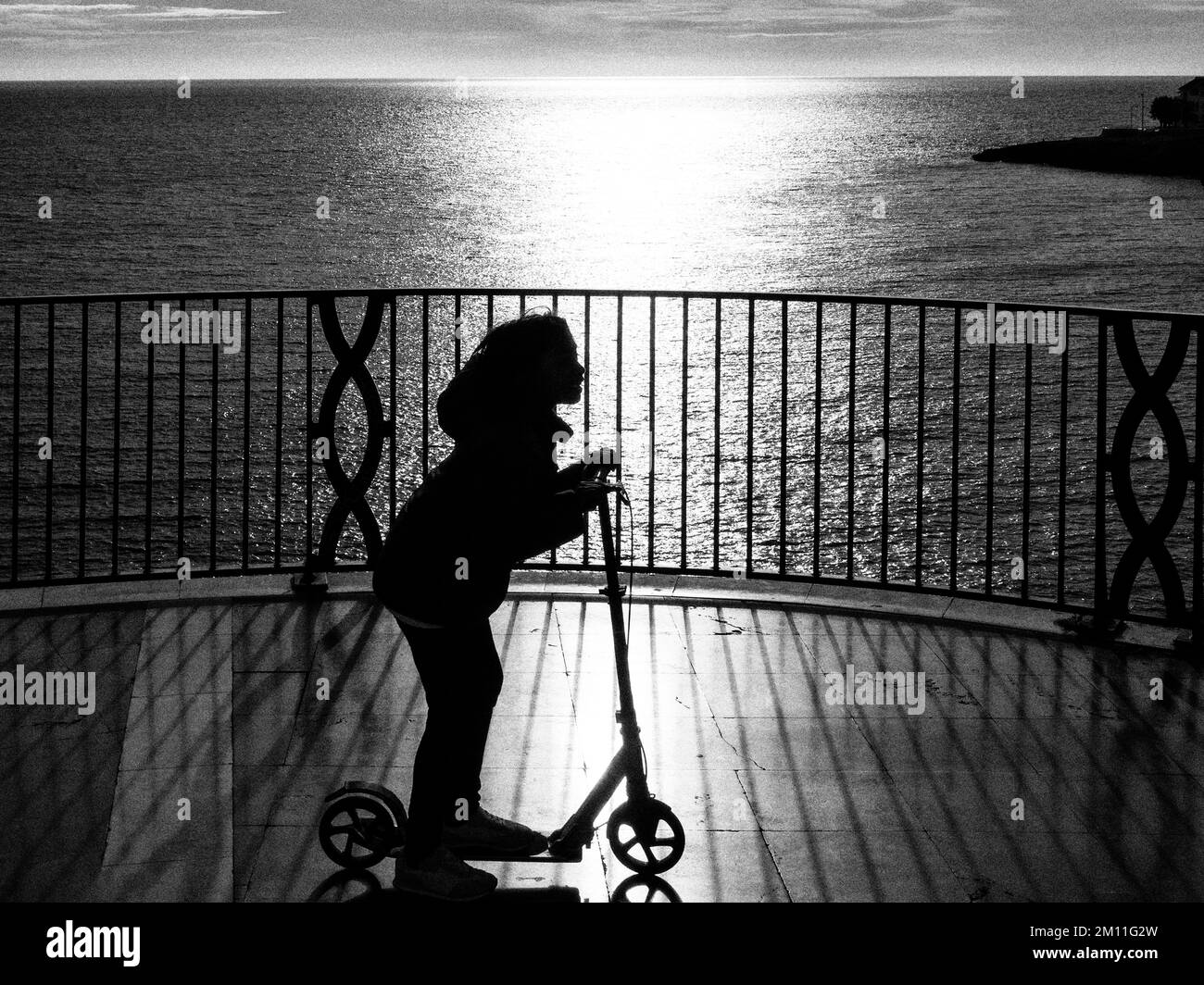 Silhouette d'une fille sur un scooter Banque D'Images