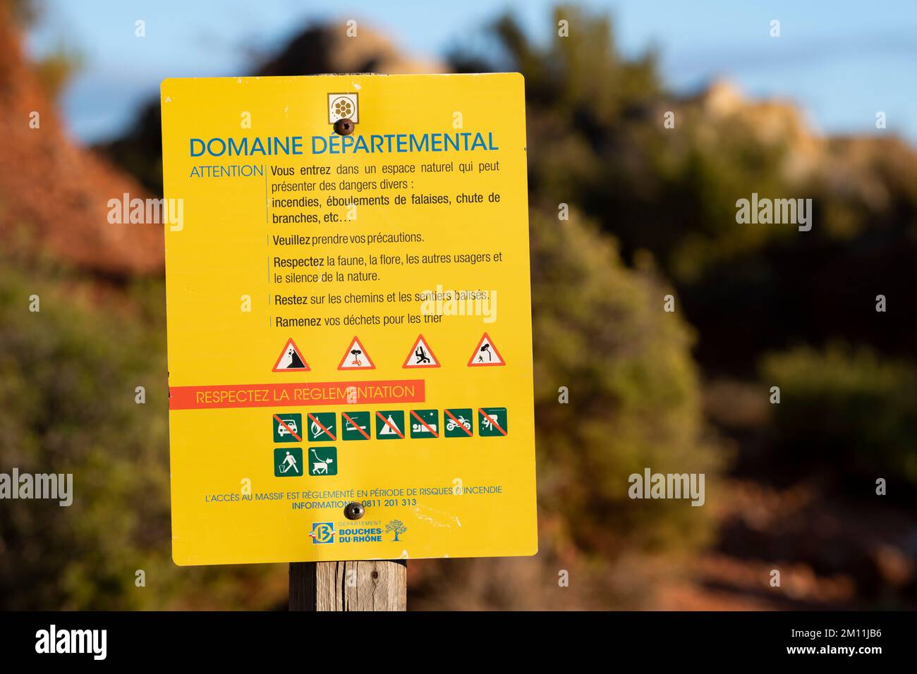 Signe jaune avec un texte français rouge et blanc dans la forêt du Sud de la France pour indiquer un domaine départemental et les règles à suivre Banque D'Images