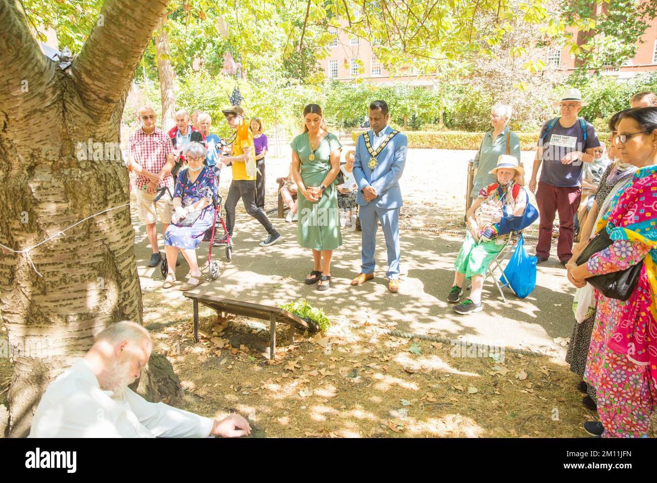 Le maire de Camden, Cllr Nasim Ali, observe un silence près du cerisier planté à la mémoire des victimes d'Hiroshima lors d'un événement à Londres. Banque D'Images