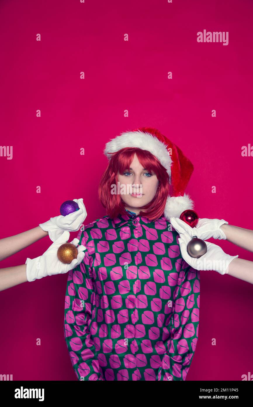 Fille avec chapeau de Noël et quatre mains avec boules d'arbre de Noël Banque D'Images