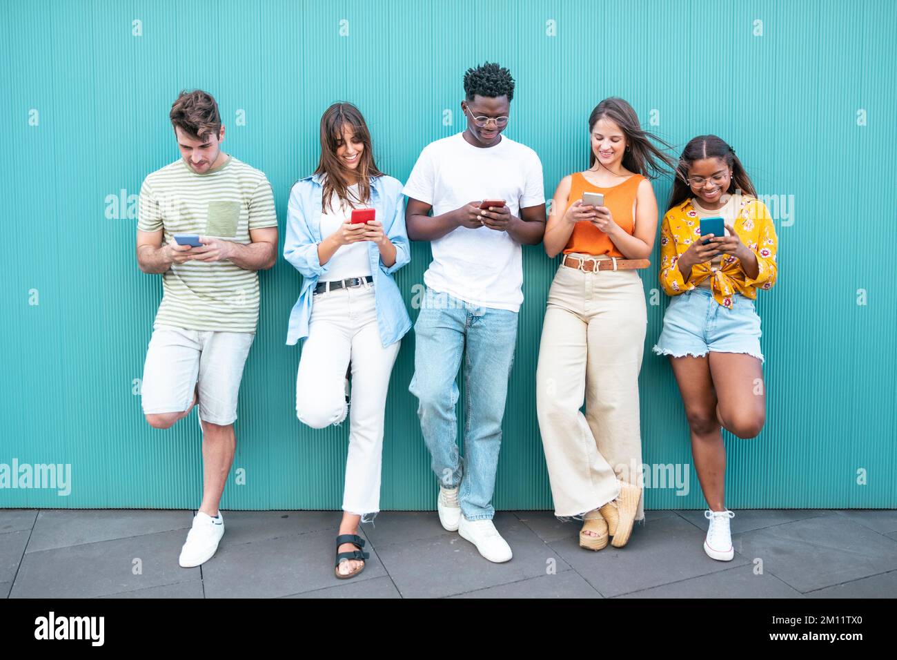 Regroupez vos amis multiraciaux à l'aide d'un smartphone à l'extérieur Banque D'Images