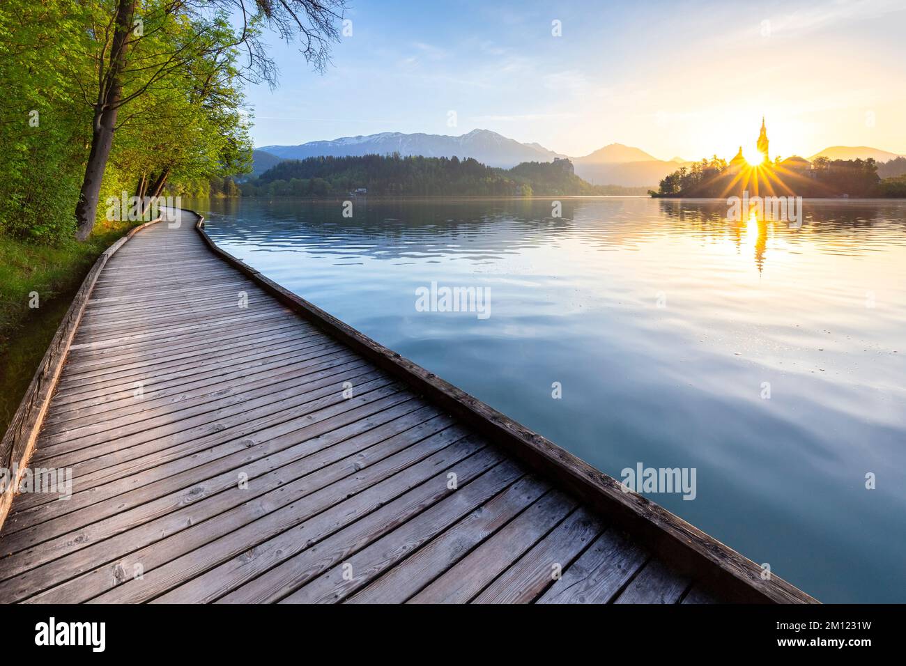 Vue sur la passerelle en bois autour du lac Bled à l'aube au printemps ...