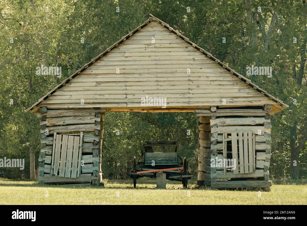 Chariot tiré par des chevaux et grange en bois vieillie dans la lumière du soleil chaude. Banque D'Images