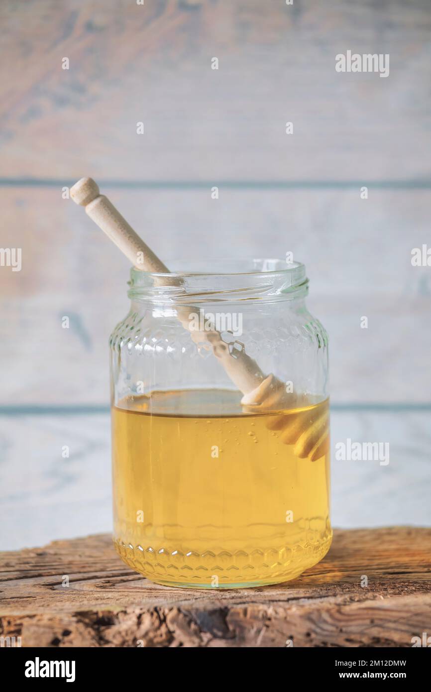 pot de miel d'abeille avec un balancier de miel sur un panneau en bois antique Banque D'Images