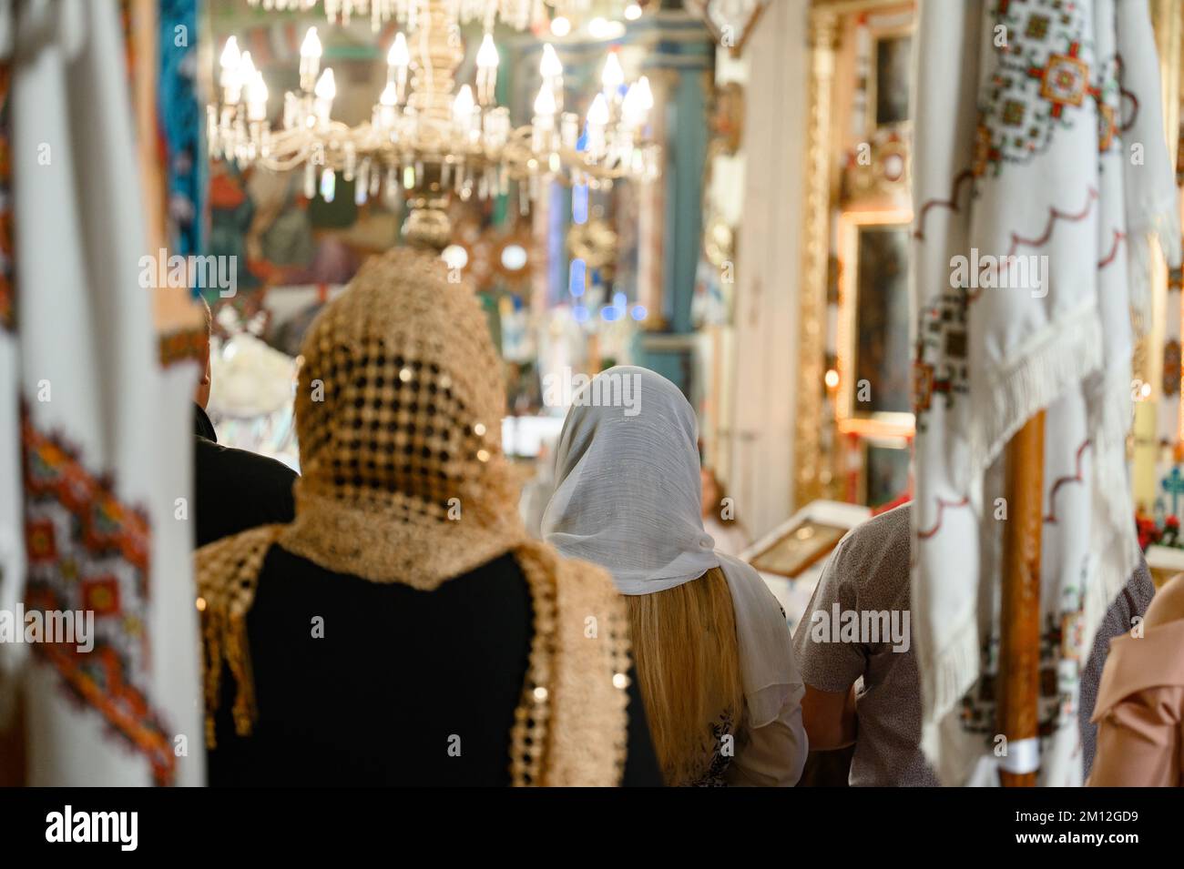 Deux femmes se tiennent dans l'église, leurs têtes couvertes de foulards, visitant le temple pendant la sainte liturgie. Banque D'Images