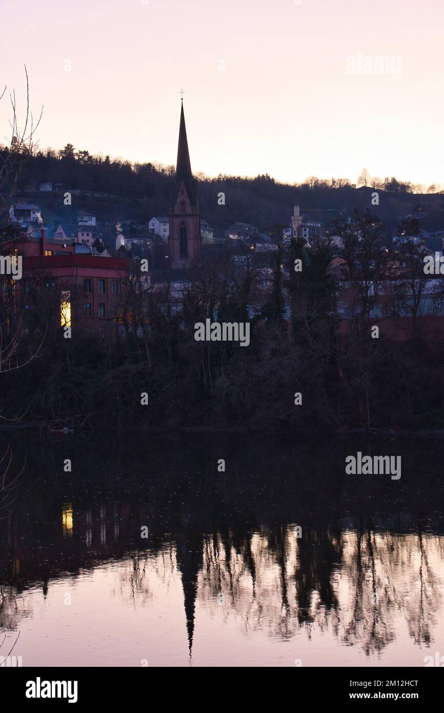 Bingen am Rhein, Allemagne - 10 janvier 2021: Eglise et autres bâtiments avec réflexion sur l'eau lors d'une soirée d'hiver en Allemagne. Banque D'Images