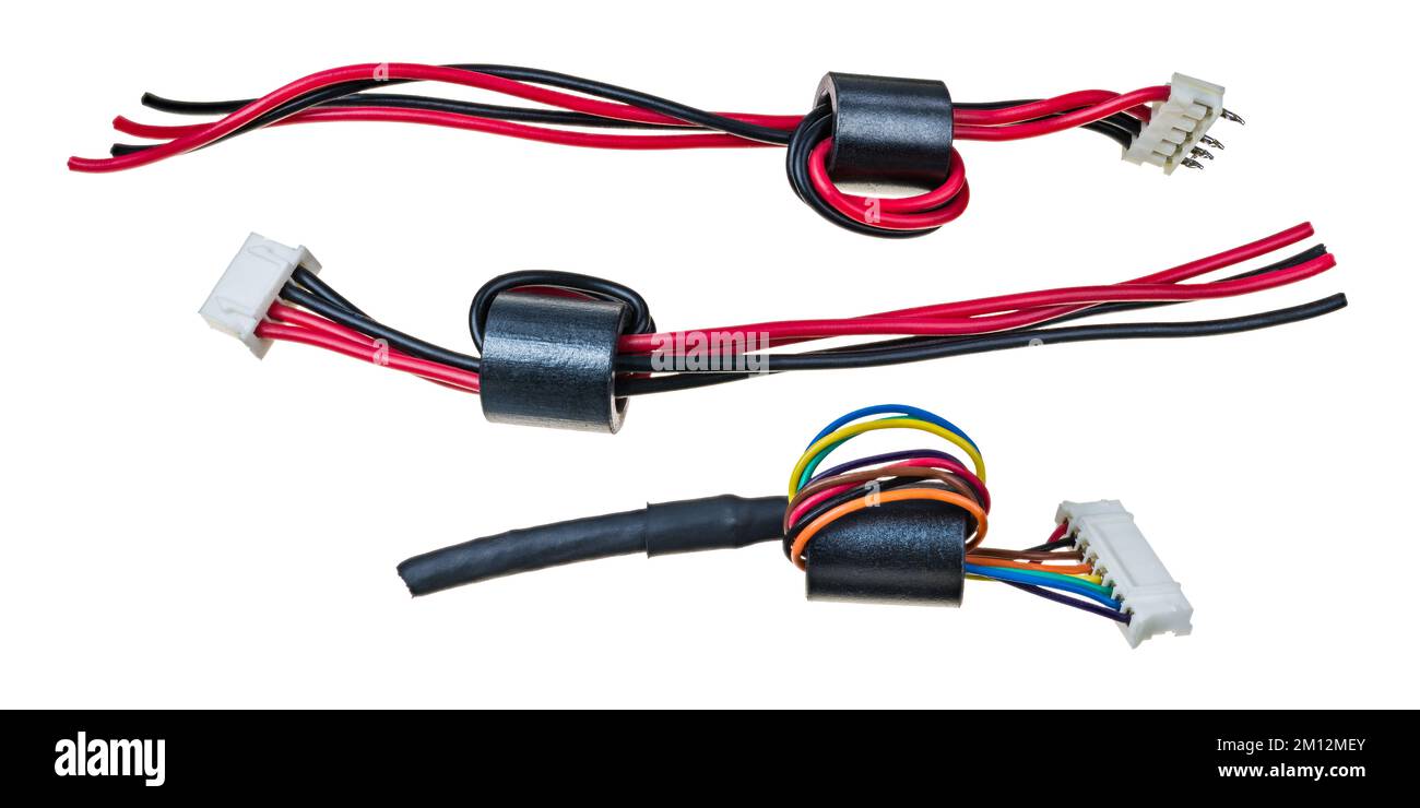 Inductances en ferrite sur fils isolés avec connecteur en plastique isolé sur fond blanc. Jeu d'inductances à noyau toroïdal. Filtre EMI pour bloquer le bruit RF. Banque D'Images