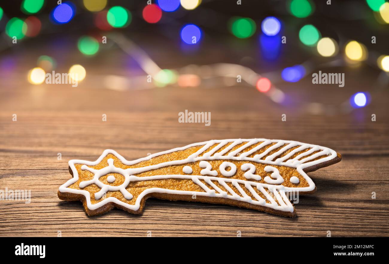 Gros plan de l'étoile de Bethléem pour le nouvel an 2023 heureux de pain d'épice de Noël doré. Biscuit de Noël doux et orné sur une texture en bois brun. Lumières À DEL. Banque D'Images