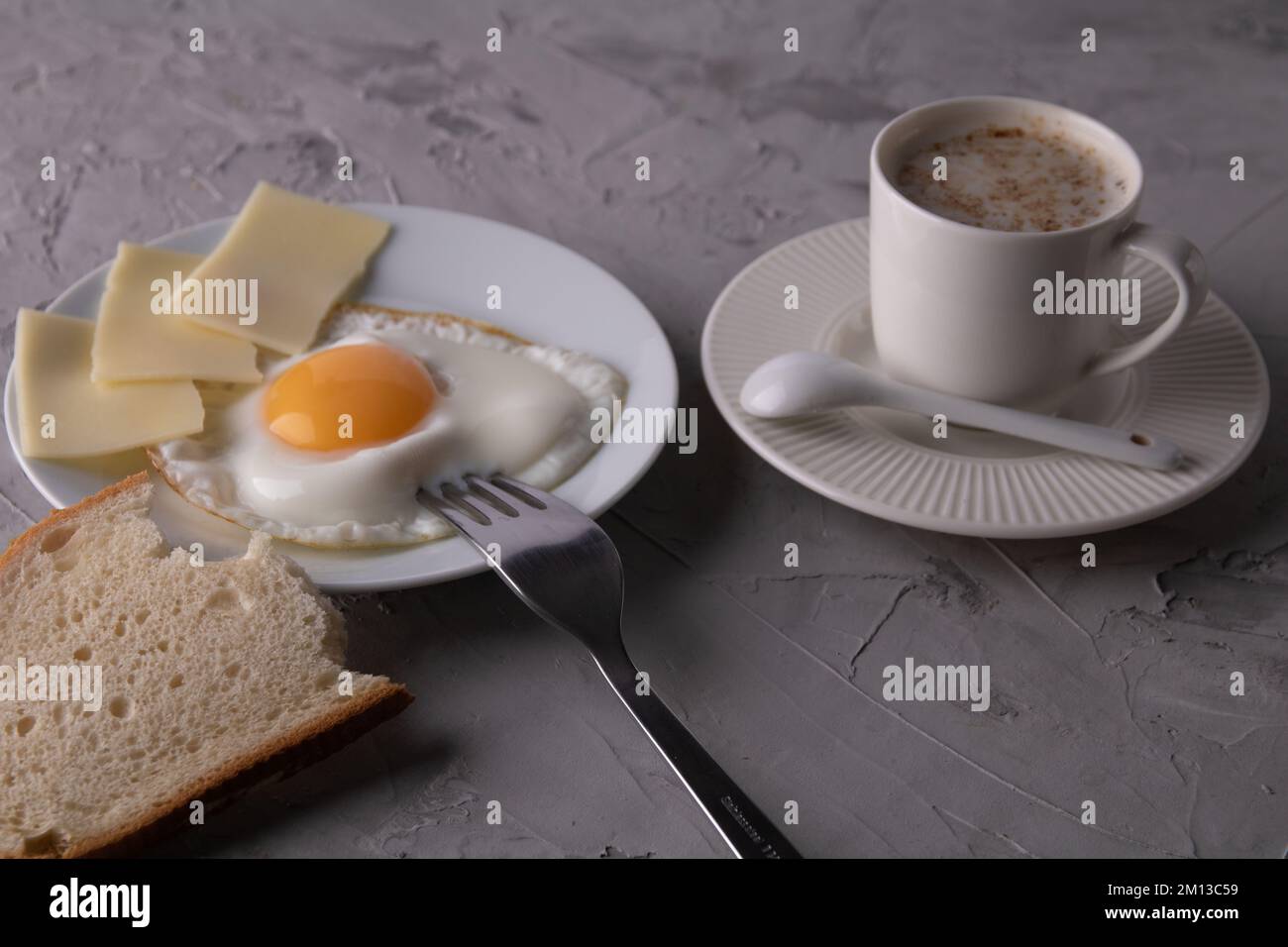 photo de l'œuf sur une assiette ronde blanche avec des tranches de fromage et une tranche de pain à côté d'une tasse de café Banque D'Images