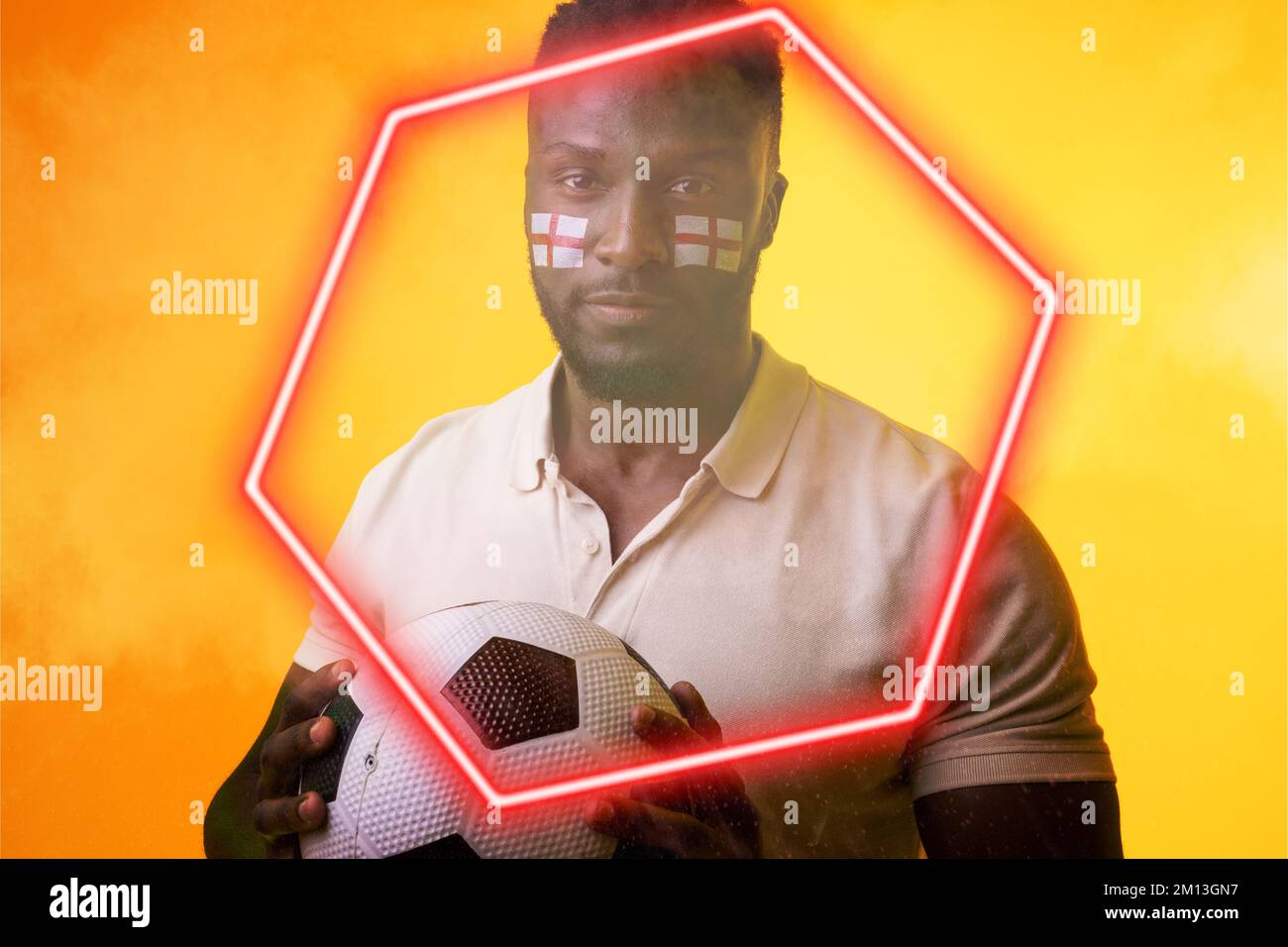 Portrait d'un fan afro-américain avec balle et peinture du visage du drapeau d'angleterre par hexagone illuminé Banque D'Images