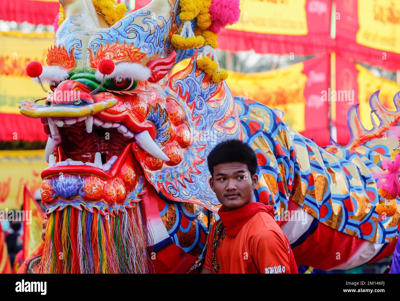 Un homme se tient à côté d'une statue d'un dragon pendant le festival Chao Por-Déesse dans le quartier de CHUM sang, à Bangkok. La grande danse de Liang Shan Mountain, est une danse traditionnelle chinoise combinant la musique, la danse et les arts martiaux réalisés par 108 danseurs qui ont peint leurs visages en différents caractères basés sur l'histoire du troupeau chinois. Le célèbre festival annuel a été créé pour la première fois en 1947 pour respecter le sanctuaire de Chao Por-Déesse. La représentation consiste en une procession d'acteurs défilant autour du district de CHUM sang. Nakhon Sawan province acrobatie et arts martiaux avec épées, matraques et Banque D'Images