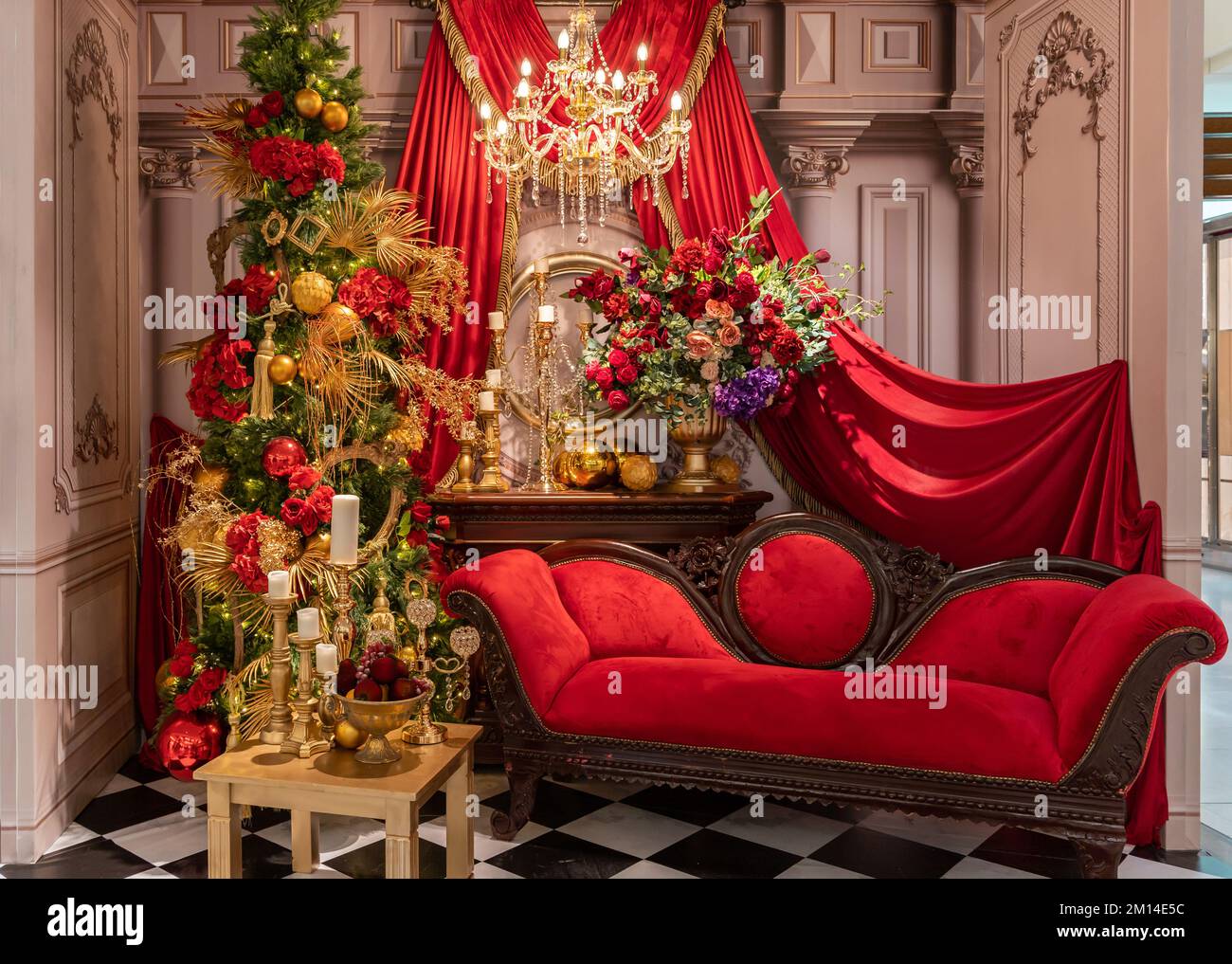 Décoration de Noël avec chaise rouge, fleurs colorées et bougies en arrière-plan. Banque D'Images