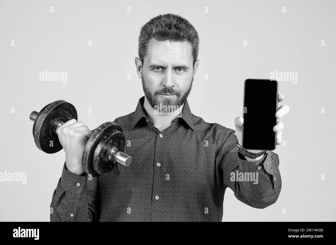 homme d'affaires barbu forte formation avec barbell et téléphone de présentation avec espace de copie, publicité Banque D'Images