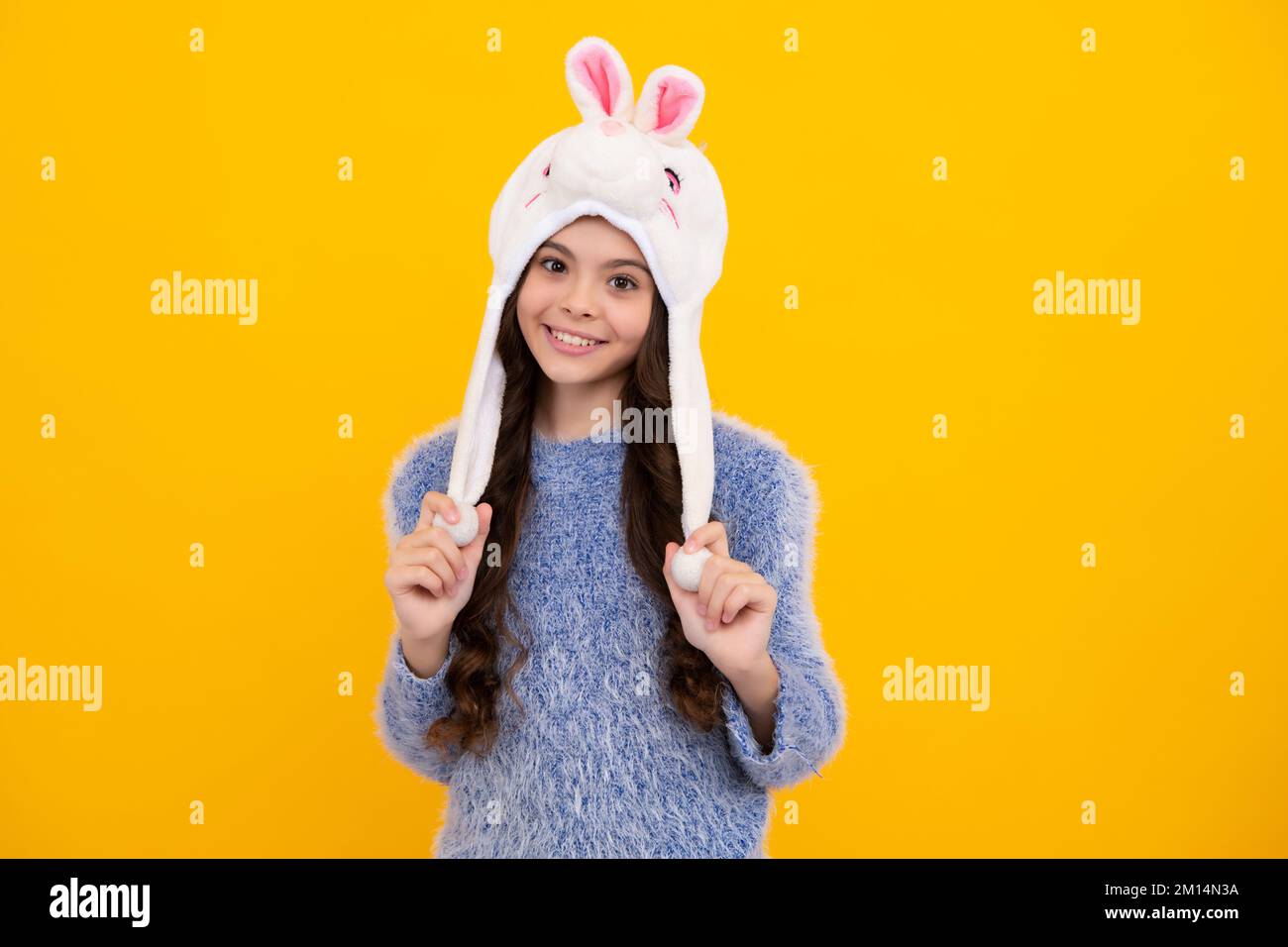 Chapeau chaud lapin. Belle jeune fille dans un chapeau d'hiver et un  chandail chaud. Un enfant sur un arrière-plan jaune isolé. Adolescent  heureux, positif et souriant Photo Stock - Alamy