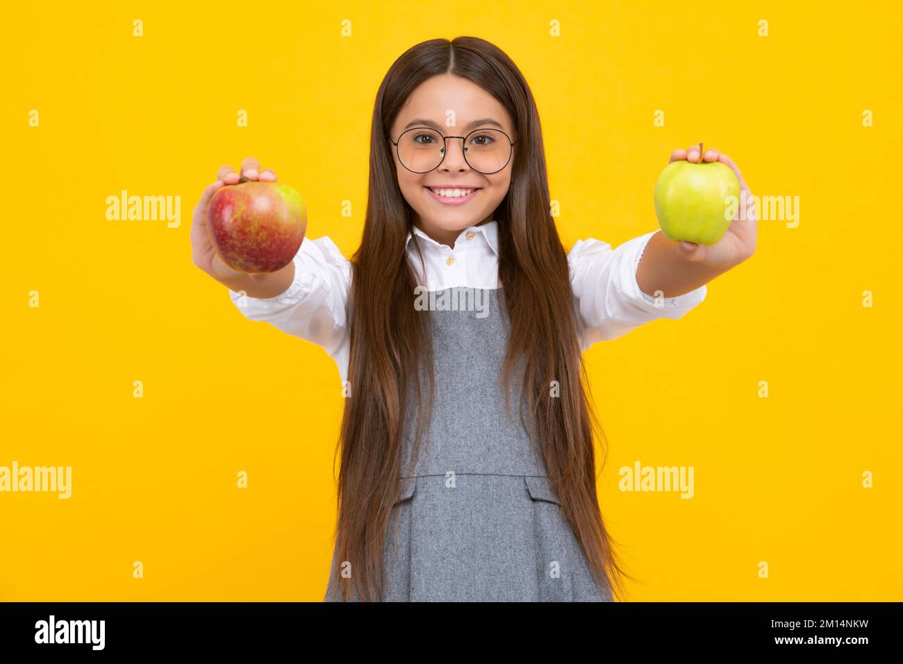 Enfant fille mangeant une pomme sur fond jaune isolé. Tennager avec des fruits. Visage de fille heureux, émotions positives et souriantes. Banque D'Images