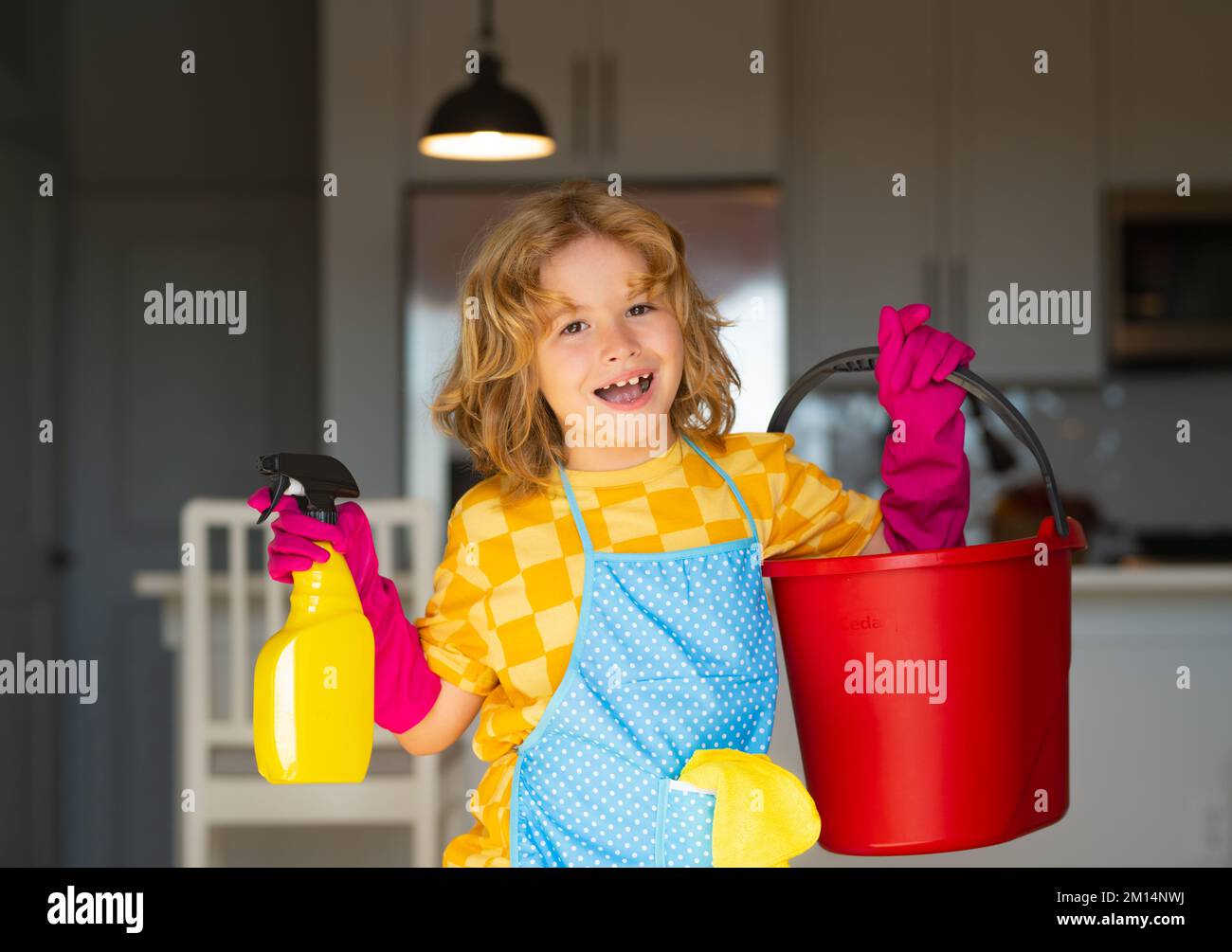 Un enfant nettoie à la maison. Nettoyage des enfants à l'aide d'une vadrouille pour faciliter les tâches ménagères. Petit garçon mignon balayant et nettoyant, sur le fond de la cuisine. Banque D'Images