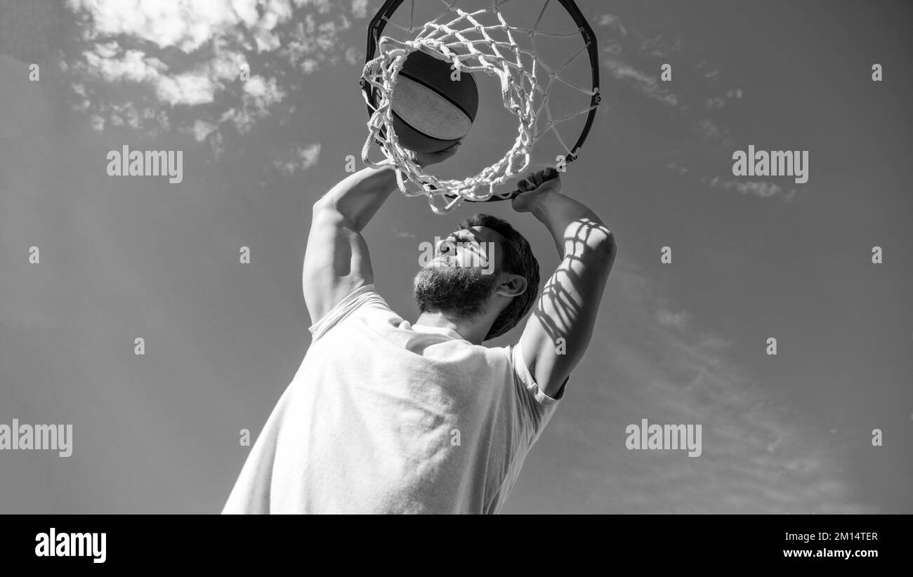 homme joueur réussi lancer ballon de basket-ball à travers le panier sur fond de ciel, l'été Banque D'Images