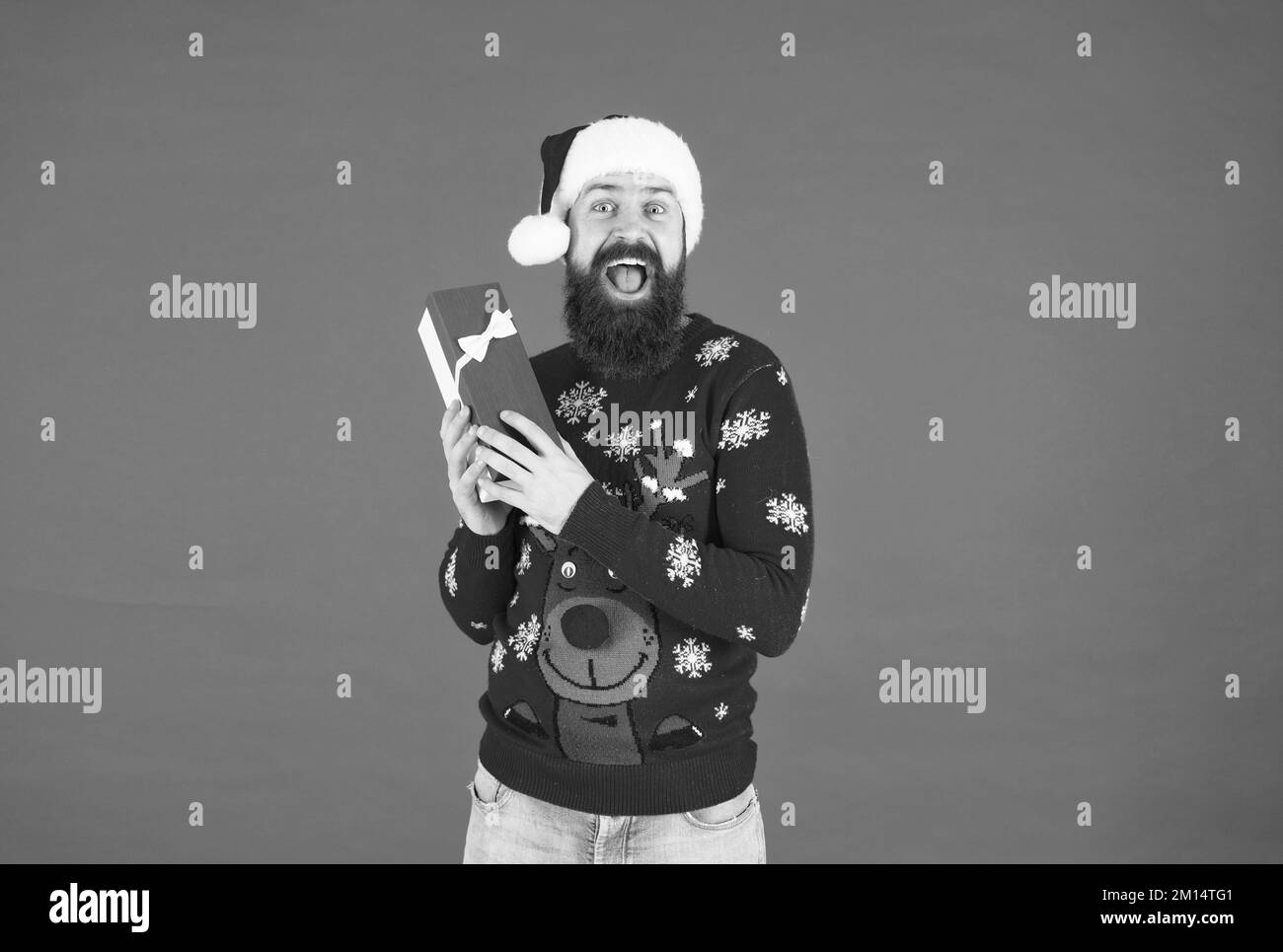 happy bearded homme hipster portant un pull tricoté drôle et chapeau de père noël et de tenir boîte présente a une idée pour célébrer la fête de noël, christma Banque D'Images