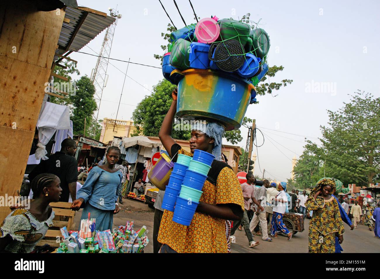 Femme porte des seaux en plastique et plusieurs autres pots en plastique sur sa tête dans la rue de Bamako , Mali , Afrique de l'Ouest Banque D'Images