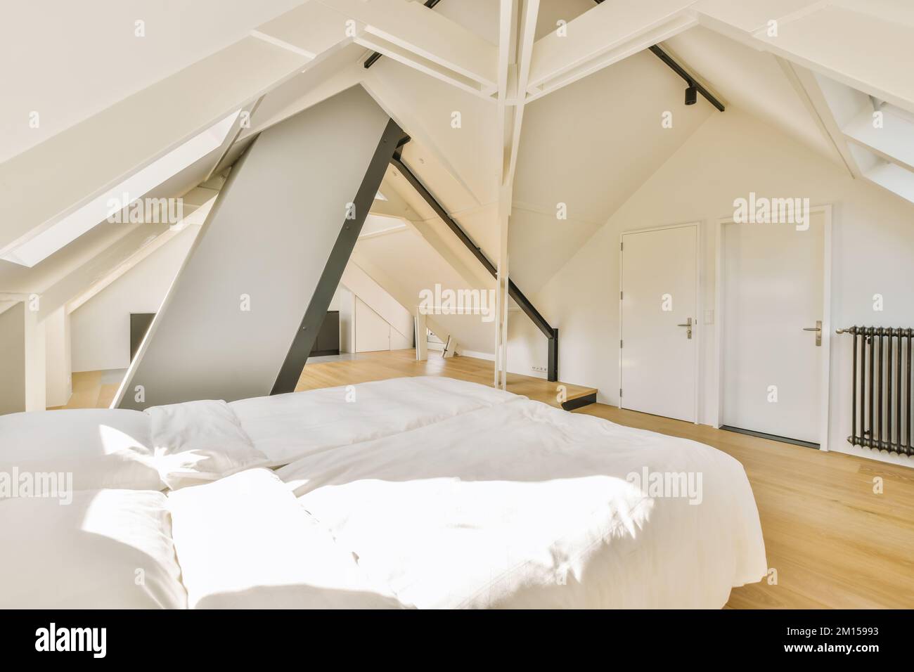 un lit dans une chambre avec des draps blancs et des oreillers sur le dessus du lit est un loft de style grenier Banque D'Images