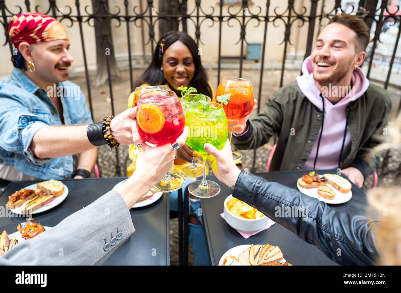 Plusieurs amis ethniques se savourent en sirotant des cocktails colorés au bar du centre-ville Banque D'Images
