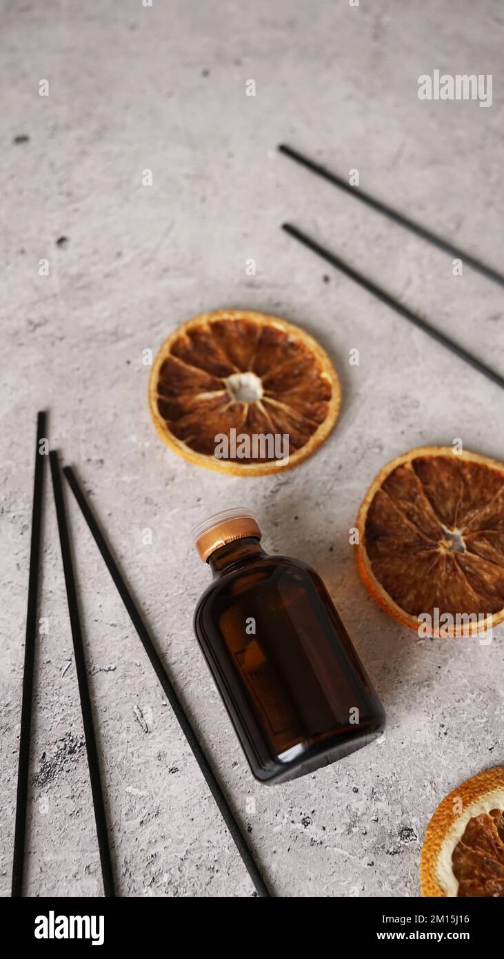 Diffuseur en roseau d'agrumes, fond sombre. Diffuseur maison. Créer une atmosphère chaleureuse à la maison. Bouteille, bâtonnets et oranges sèches. Photo verticale Banque D'Images Diffuseur en roseau d'agrumes, fond sombre. Diffuseur maison. Créer une atmosphère chaleureuse à la maison. Bouteille, bâtonnets et oranges sèches. Photo verticale Banque D'Images