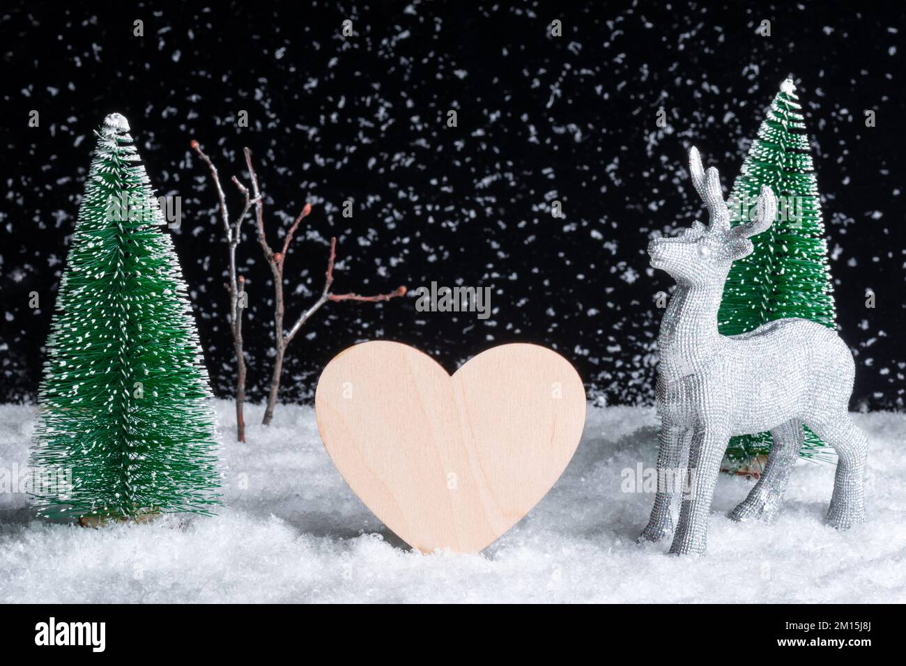 Carte de Noël créative. Artisanat à partir d'arbres jouets dans une chute de neige la nuit, un coeur en bois et un cerf de Noël. Le concept des relations dans le nouveau yea Banque D'Images