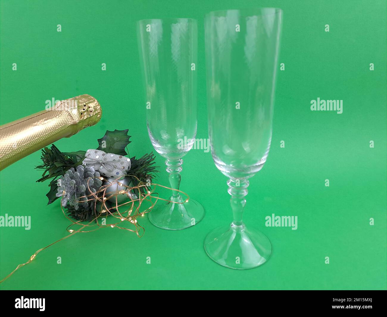 Nouvel an une bouteille de vin mousseux en verre vert et doré avec verres, gobelets. Cartes de vœux festives du nouvel an, avec petites lumières. Banque D'Images