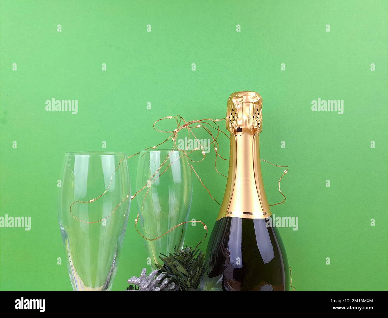 Nouvel an une bouteille de vin mousseux en verre vert et doré avec verres, gobelets. Cartes de vœux festives du nouvel an, avec petites lumières. Banque D'Images