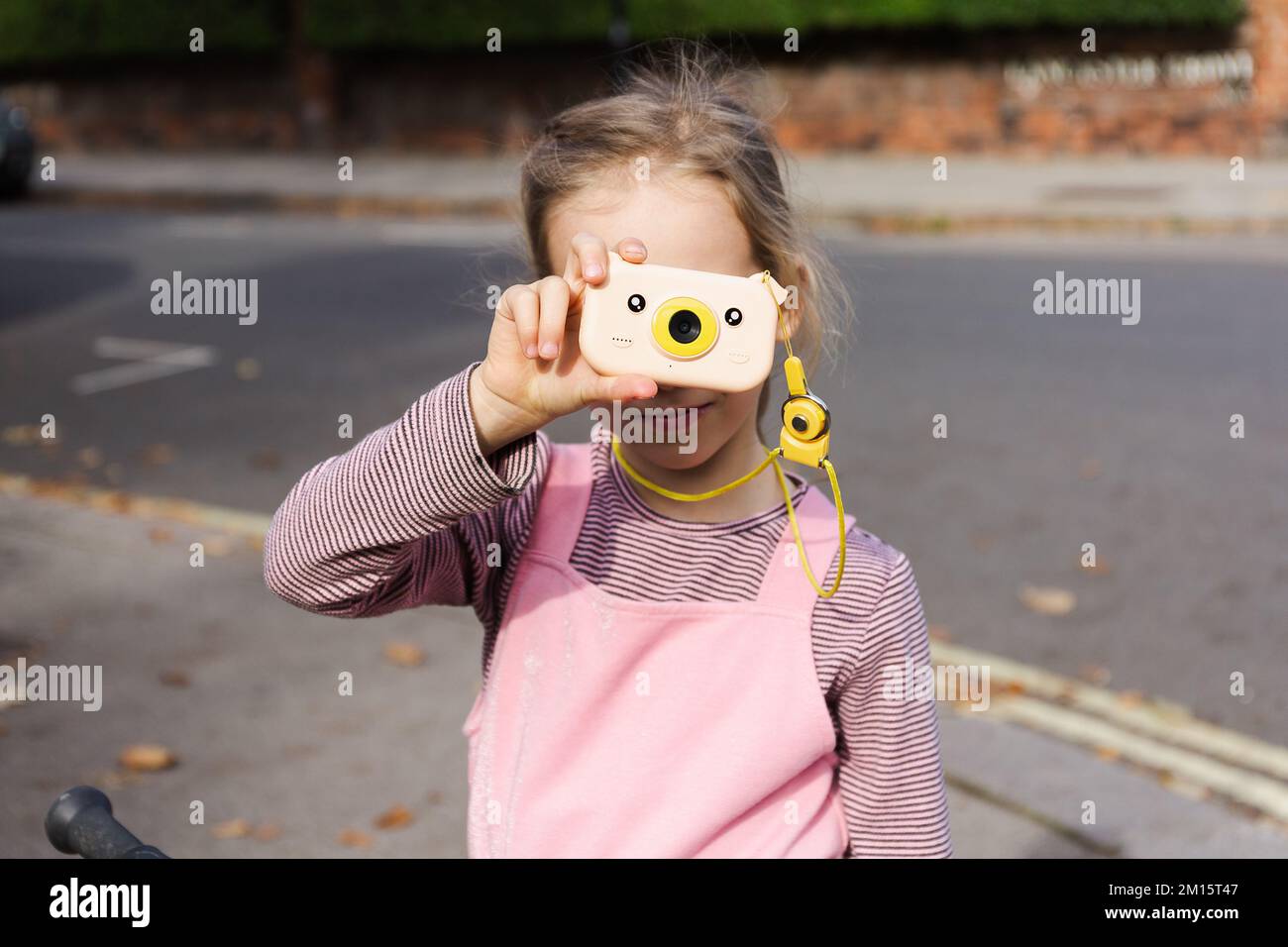 Jeune fille assise à vélo et prenant des photos avec un appareil photo « visez et photographiez » le jour de l'automne dans la rue Banque D'Images