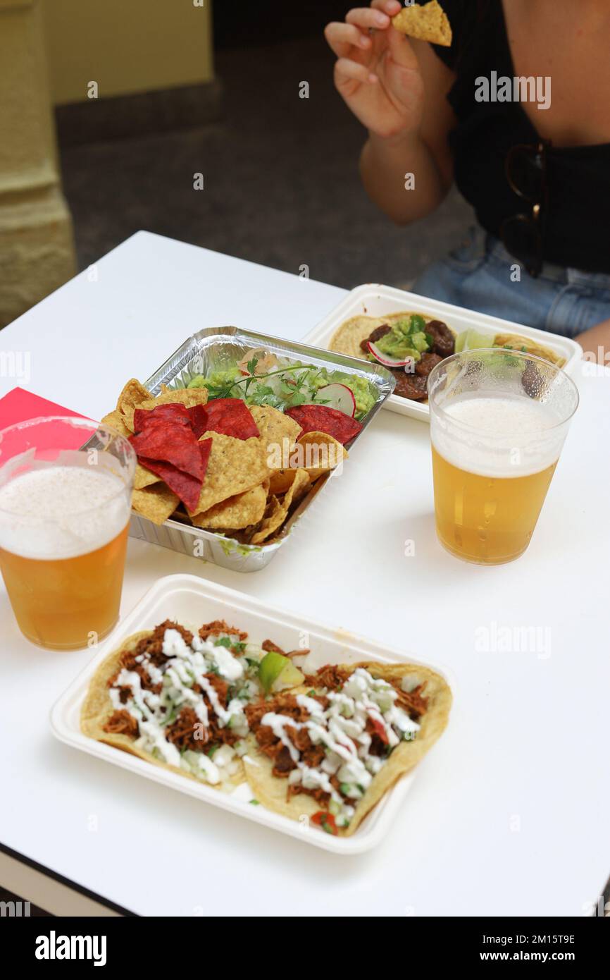 Au-dessus de nachos appétissants avec salade et tacos avec sauce sur les assiettes servies avec des verres de bière dans le restaurant Banque D'Images