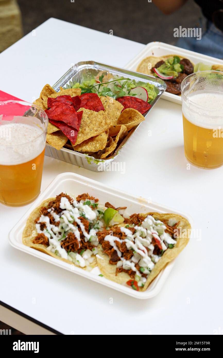 Au-dessus de nachos appétissants avec salade et tacos avec sauce sur les assiettes servies avec des verres de bière dans le restaurant Banque D'Images