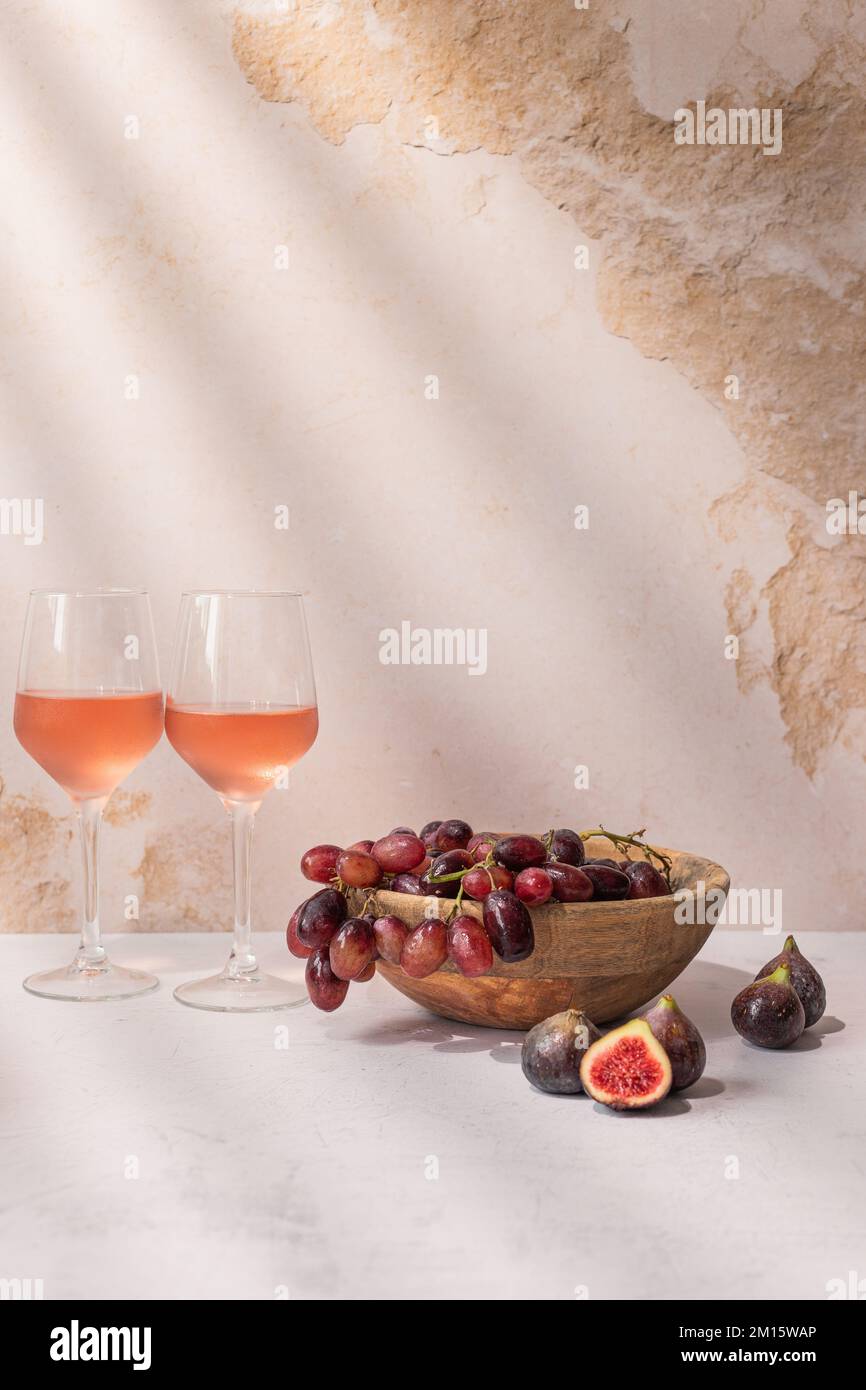 Verres de boisson rouge placés sur la table avec un bol de raisins et de figues Banque D'Images
