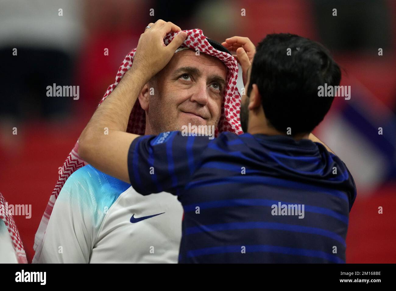 Un fan de l'Angleterre a son shemagh ajusté par un fan de la France dans les tribunes avant le match de quart-finale de la coupe du monde de la FIFA au stade Al Bayt à Al Khor, Qatar. Date de la photo: Samedi 10 décembre 2022. Banque D'Images