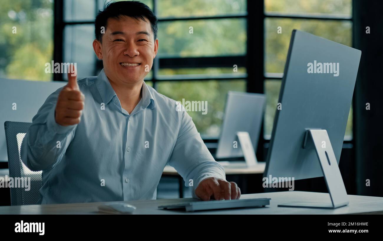 Joyeux homme d'affaires asiatique mature chinois japonais homme de bureau de travail sur ordinateur faire le pouce vers le haut geste bon beau super symbole recommander haut Banque D'Images