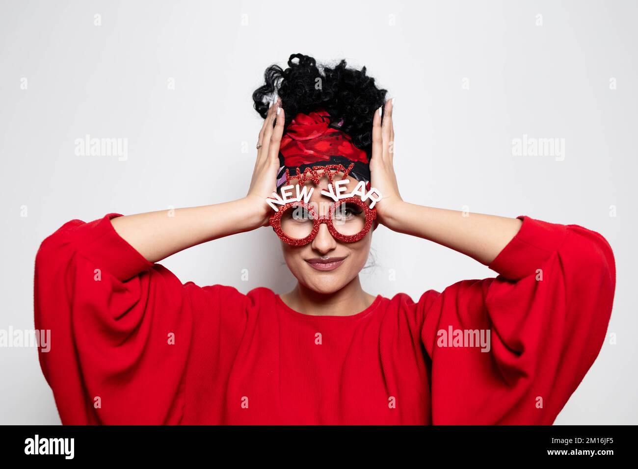 Belle jeune fille en forme de curly avec des lunettes prop du nouvel an et une coiffure de bandana Banque D'Images