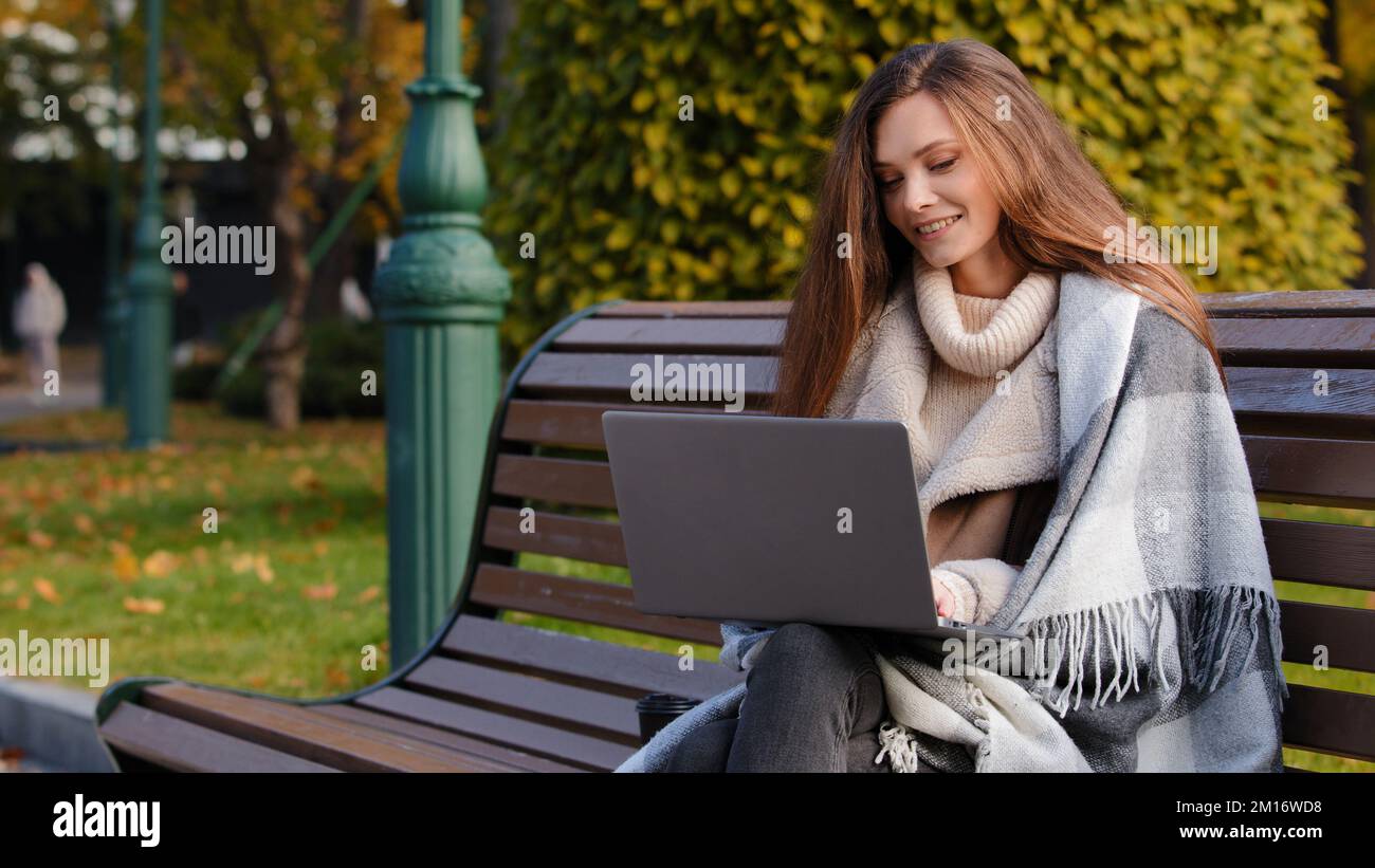 Caucasien jeune femme d'affaires étudiant s'asseoir sur le banc dans le parc de chat en ligne par ordinateur portable vidéo appel conférence négociation en utilisant webcam d'ordinateur pour Banque D'Images