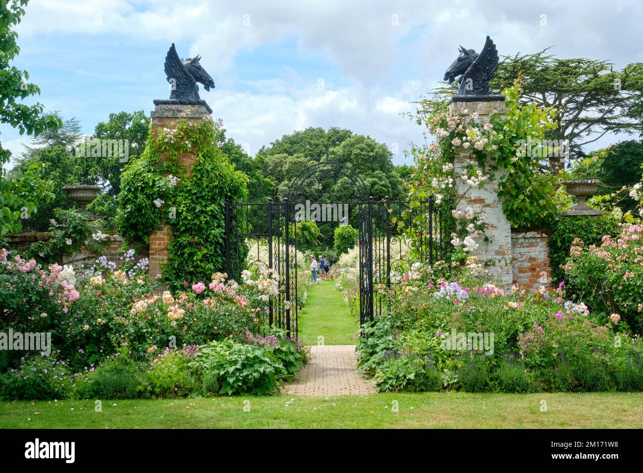 Été vue sur le paysage de l'entrée en métal ornée aux frontières herbacées dans le Helmingham Hall et les jardins du Suffolk Banque D'Images
