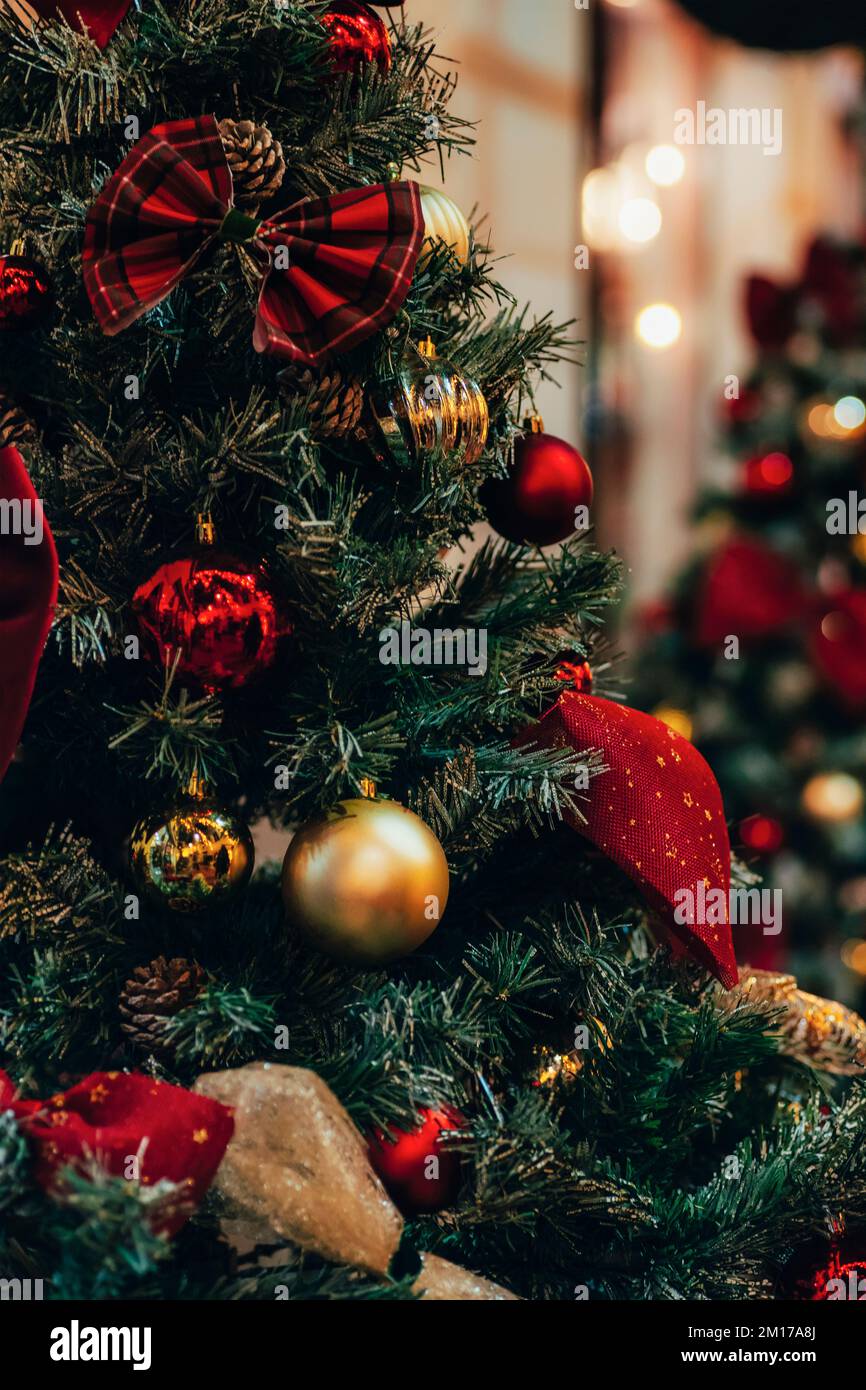 Superbes décorations de Noël sur sapin avec boules dorées et rouges et lumières de Noël, gros plan. Banque D'Images