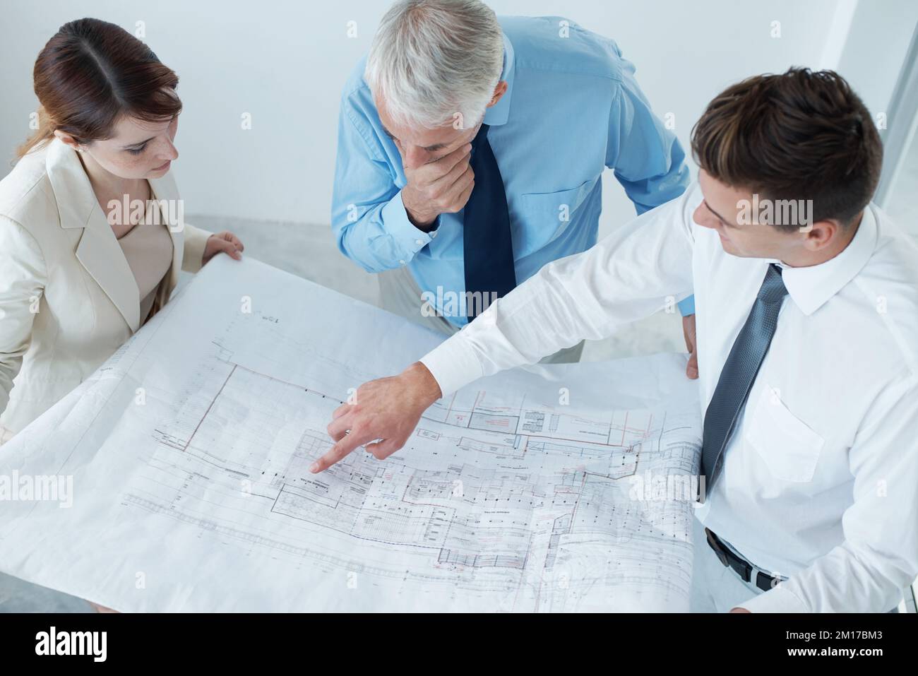 finalisation des nouveaux plans du siège social. Photo d'un trois hommes d'affaires en train de faire des plans-plans. Banque D'Images
