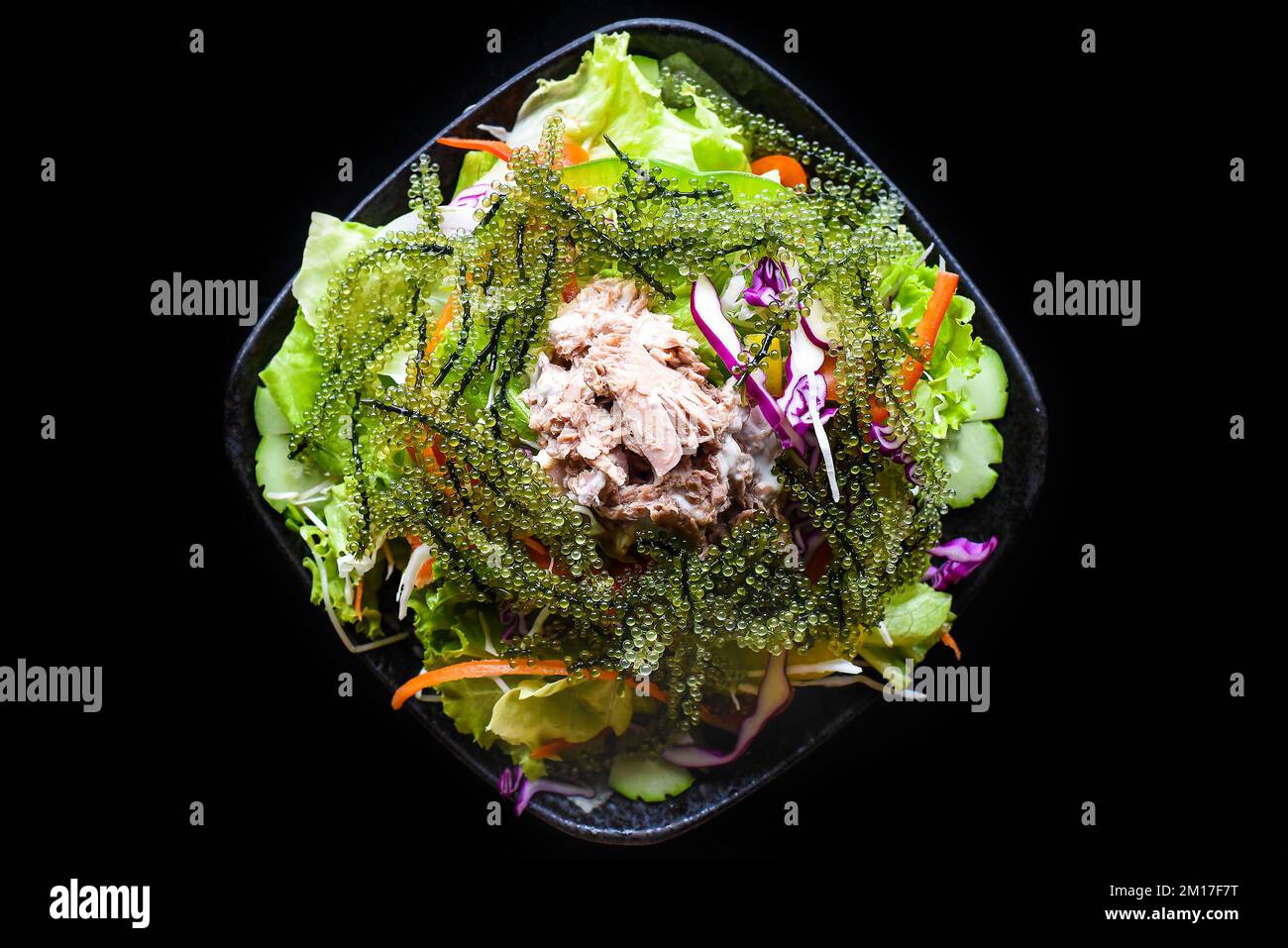 Salade vietnamienne fraîche avec légumes, thon et raisin de mer sur fond noir vue de dessus Banque D'Images